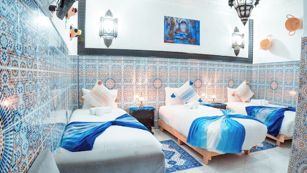 Habitación de hotel con dos camas, paredes con diseño y faroles decorativos.