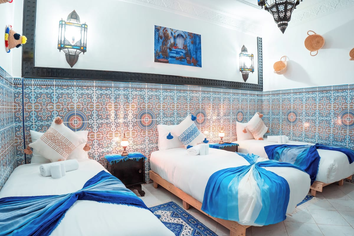 A hotel room with four beds, patterned tile walls, and decorative lanterns.
