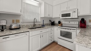 A modern kitchen with white cabinets, a built-in microwave, a coffee maker, and a toaster.