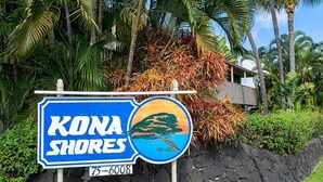 A sign for Kona Shores with a scenic view of a tree and ocean. - Cozy Ocean View 1-bedroom, 1 bath condo in awesome Kailua-Kona with AC (Kailua-Kona)