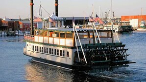 A steamboat docked at a marina with multiple boats, a building with a red roof, and a sign reading "Captain River Queen". - Welcome to a Cozy Waterfront Condo in Charming Cambridge, MD (Cambridge)