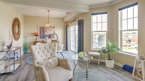 A spacious living room with a large window, a chandelier, and a view of the city. - Welcome to a Cozy Waterfront Condo in Charming Cambridge, MD (Cambridge)
