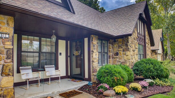 A stone house with a covered porch, two chairs, and a front door with a wreath. - Nice 4-bedroom house with large rooms in Broken Arrow (Broken Arrow)