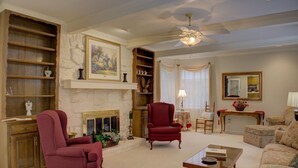 A spacious living room with a fireplace, a ceiling fan, and a large painting. - Nice 4-bedroom house with large rooms in Broken Arrow (Broken Arrow)