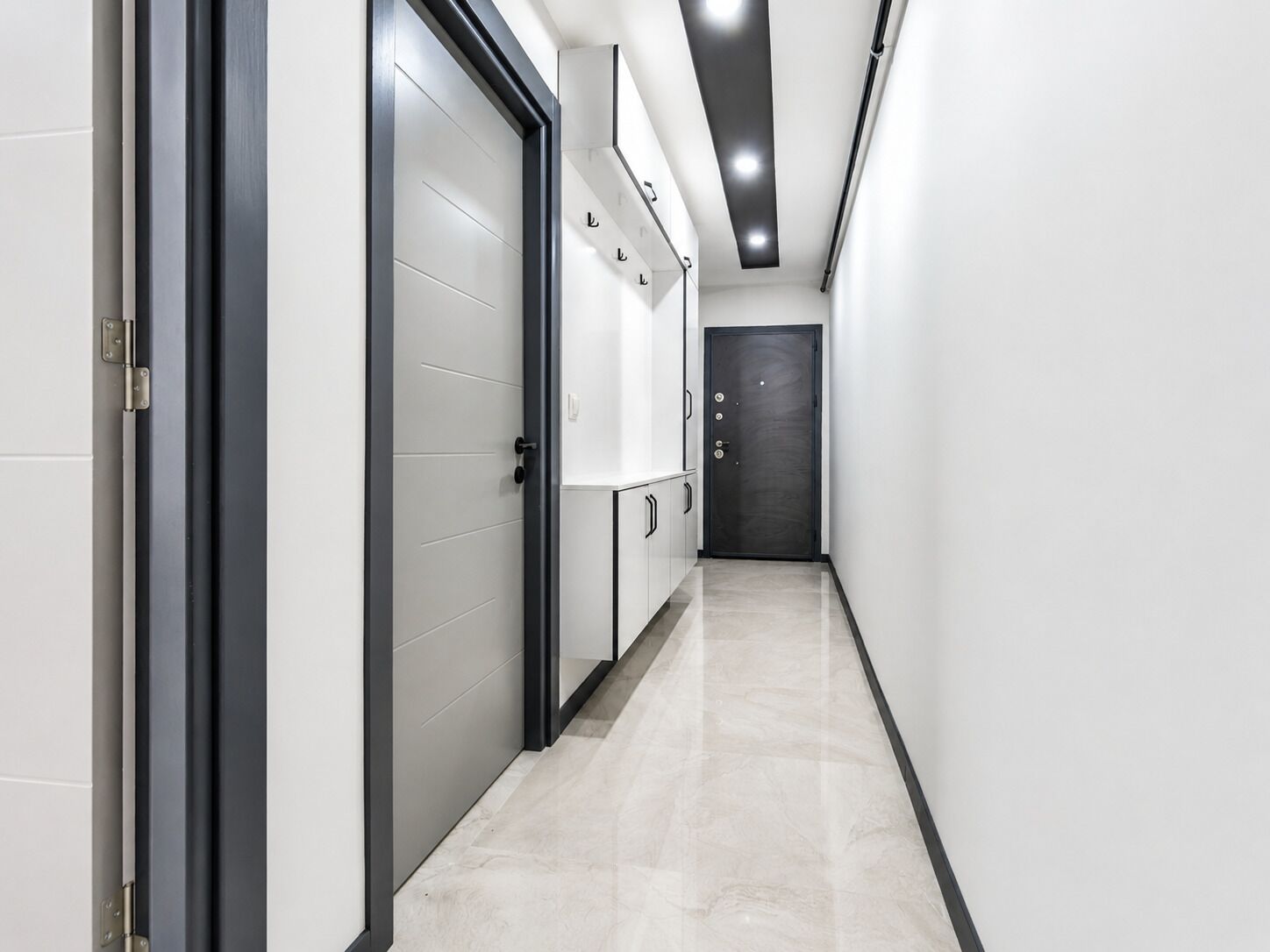 A hallway with a door, cabinets, and a light fixture.