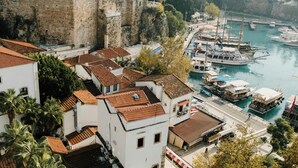 Un pueblo costero con edificios históricos, un puerto deportivo y barcos amarrados.