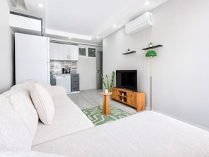 Un salon moderne avec un canapé, un téléviseur et un petit meuble en bois.