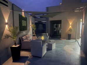 An outdoor patio area with seating, potted plants, and ambient lighting.