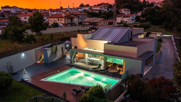 A modern house with a swimming pool, outdoor seating, and a patio area.