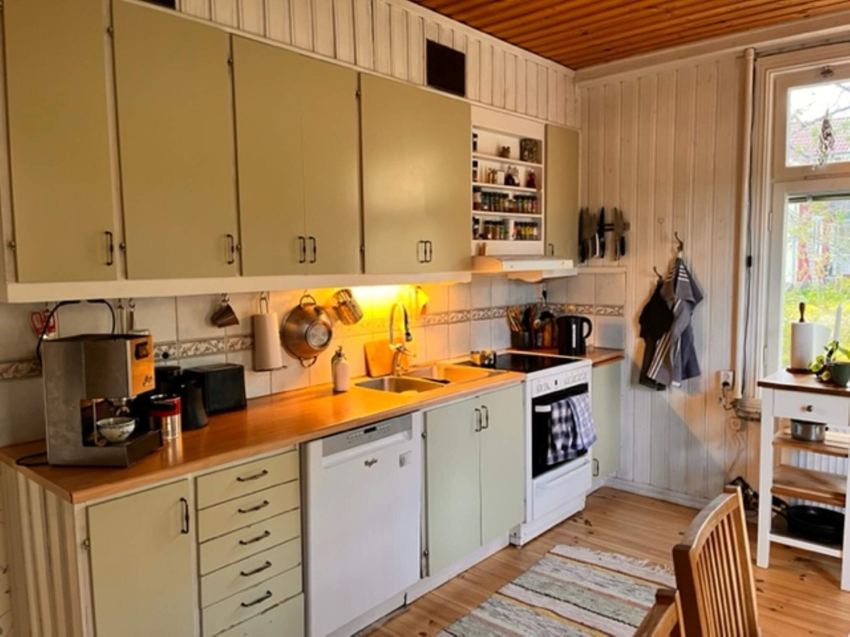 A kitchen with white cabinets, a dishwasher, a stove, and a sink.