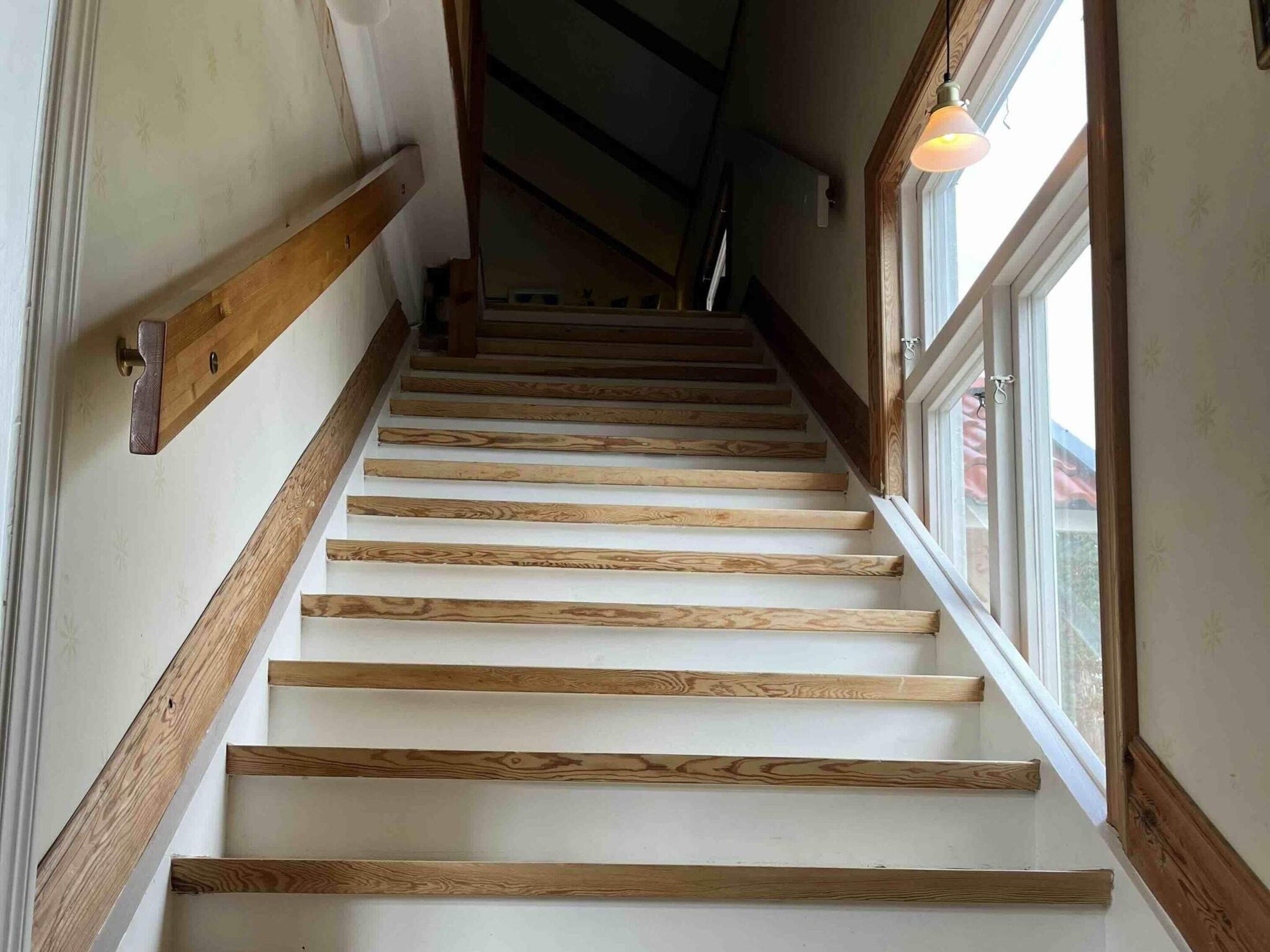 A staircase with wooden steps and a handrail, leading to a room with a window.