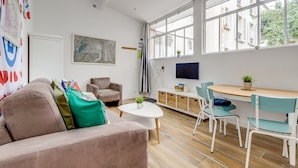 Una sala moderna con un sofá, una mesa de centro, un televisor y un comedor con sillas y una mesa.
