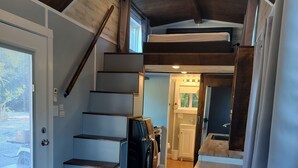 Une cuisine moderne dotée d’un îlot central, d’un escalier menant à un étage supérieur et offrant une vue sur l’extérieur grâce à une grande fenêtre.