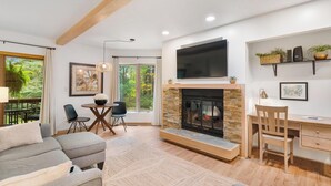 Una sala de estar moderna con chimenea, un televisor grande y una zona de escritorio.