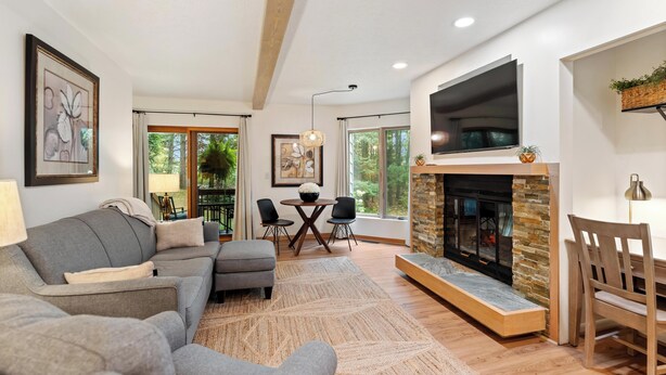Una sala de estar moderna con chimenea, un sofá, un comedor y ventanas amplias.