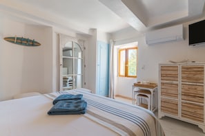 Quarto com cama, guarda-roupa, televisão e janela com cortinas.