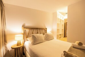 A neatly made bed with pillows, a bedside lamp, and a wooden headboard in a hotel room. - Luxury villa with exceptional panoramic views in Porto Vecchio (Porto-Vecchio)