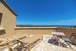 A terrace with wicker lounge chairs and a table, overlooking a scenic landscape. - Luxury villa with exceptional panoramic views in Porto Vecchio (Porto-Vecchio)