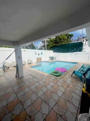 A swimming pool area with tiled flooring, a pool, and several lounge chairs. - Casa Dos Palmas-House with Solar System and just 8 Min from the Airport. (San Juan)