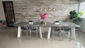 Un espace de restauration moderne avec un mur en marbre, une longue table et des chaises blanches.