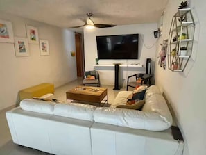 A living room with a white sofa, a coffee table, a TV, and a bookshelf. - Casa Dos Palmas-House with Solar System and just 8 Min from the Airport. (San Juan)