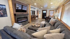 A modern living room with a large sectional sofa, a fireplace, and a dining area.