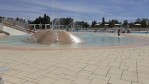 Une piscine agrémentée d’un élément décoratif aquatique et d’une allée dallée.