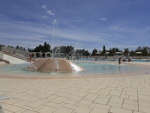 Ein Schwimmbad mit Wasserspiel und einem gefliesten Gehweg.