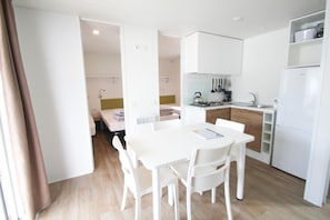 A modern, well-lit kitchen with white cabinetry, a dining table with chairs, and a small island with a sink.