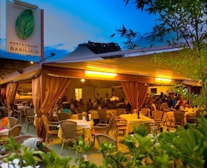 A restaurant named 'Basilico' with outdoor seating and a covered area.
