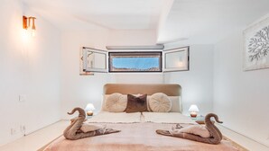 A bedroom with a bed, two lamps, a window, and a wall-mounted mirror. - Modern apartment with private pool and beautiful views (Mogán)