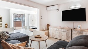 Un salon moderne avec un canapé, une table basse ronde et un téléviseur fixé au mur.