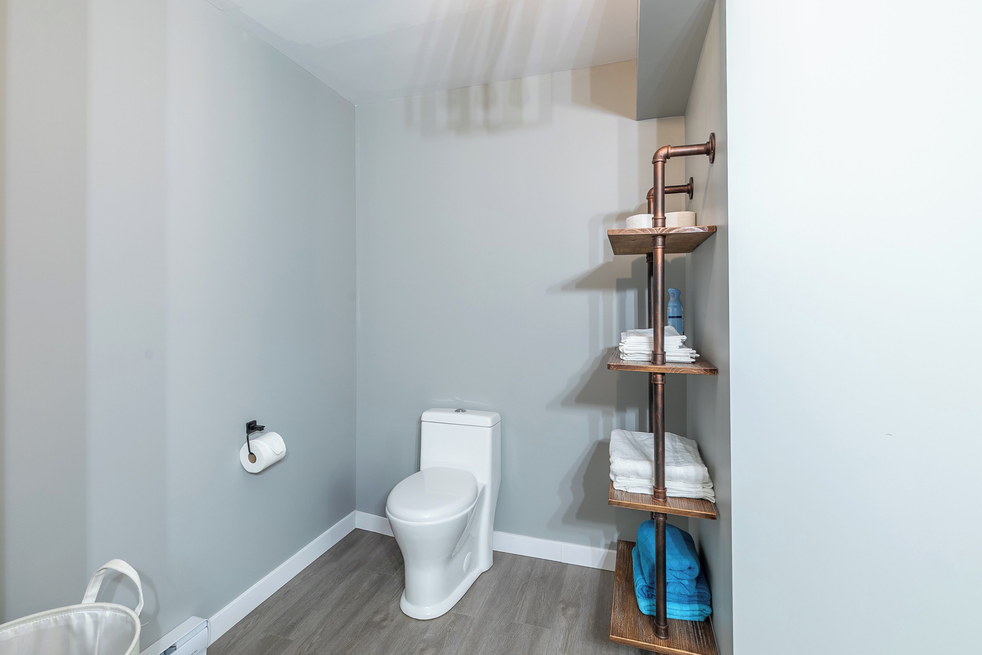 Un baño pequeño con inodoro blanco, toallero con toallas dobladas y dispensador de papel higiénico en la pared.