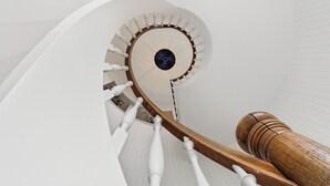 Un escalier en colimaçon avec des balustrades blanches et des rampes en bois.