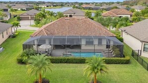 A residential area with a house featuring a large glass enclosure with a pool. - Looking for last minute X-mas plans?  Beautiful home in Fort Myers - 7 days min. (Fort Myers)