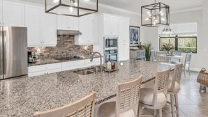 A modern kitchen with granite countertops, stainless steel appliances, and a central island with bar stools. - Looking for last minute X-mas plans?  Beautiful home in Fort Myers - 7 days min. (Fort Myers)