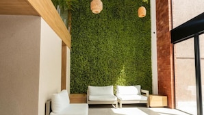 A modern interior with a green wall, white furniture, and natural light. - Sereno Hotel (Cabo Frio)