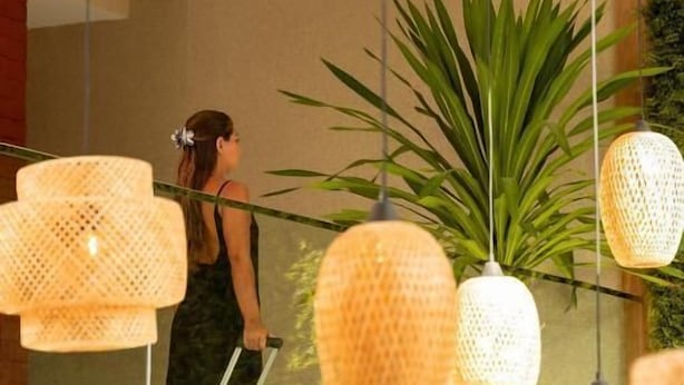 A room with a large mirror, hanging wicker lamps, and a potted plant. - Sereno Hotel (Cabo Frio)