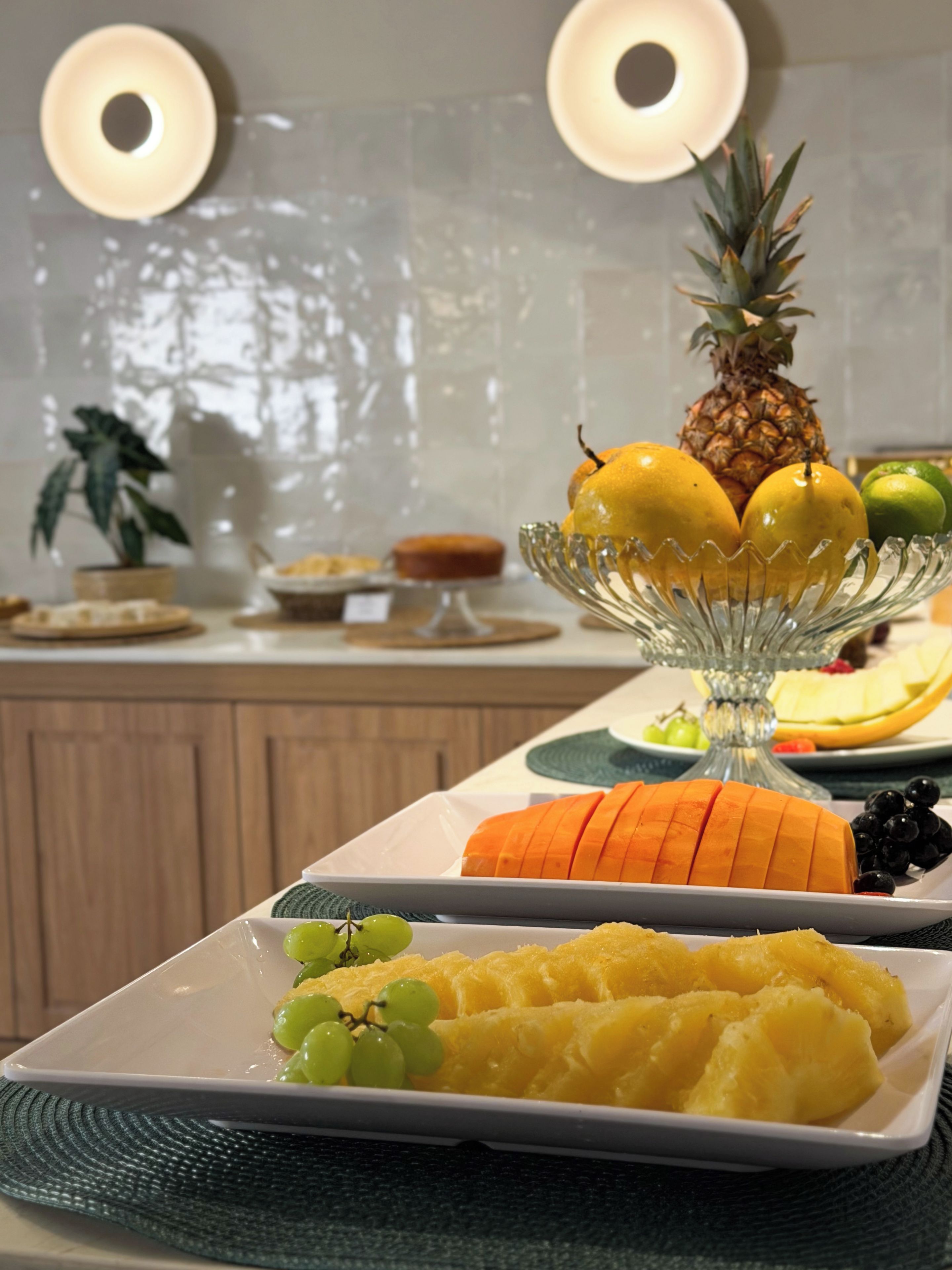 A fruit platter with pineapple, lemons, and grapes on a table.