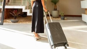 A modern interior with a staircase, a woman with a suitcase, and hanging pendant lights. - Sereno Hotel (Cabo Frio)