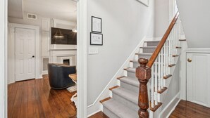 Un escalier avec des balustrades en bois et une main courante, menant à un palier où se trouve une porte blanche et un certificat encadré accroché au mur.