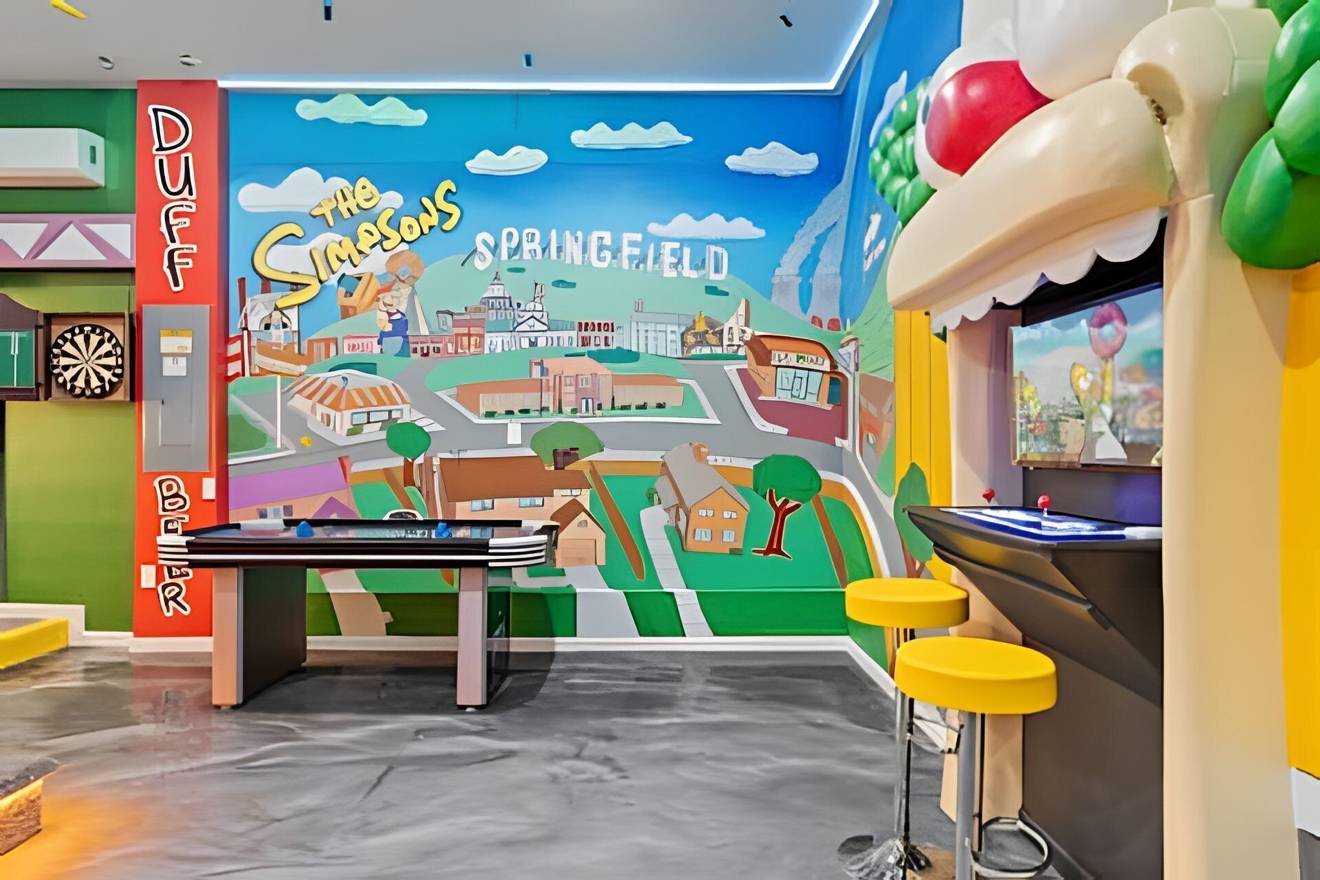 Et rum med dartskive, billardbord og et muralmaleri af Springfield.