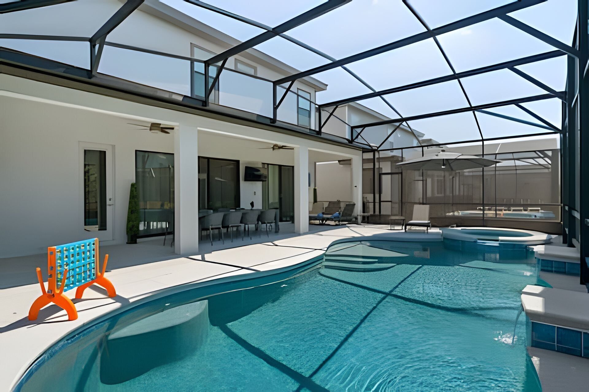 An indoor swimming pool with a glass ceiling, seating area, and a view of the sky.