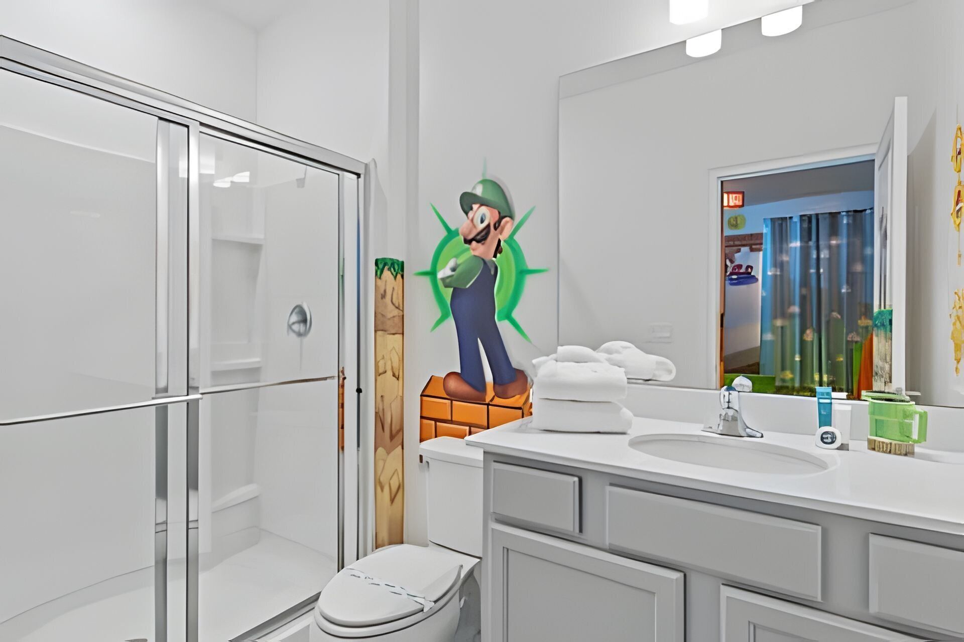 A modern bathroom with a glass shower enclosure, a toilet, a sink with toiletries, and a large mirror.