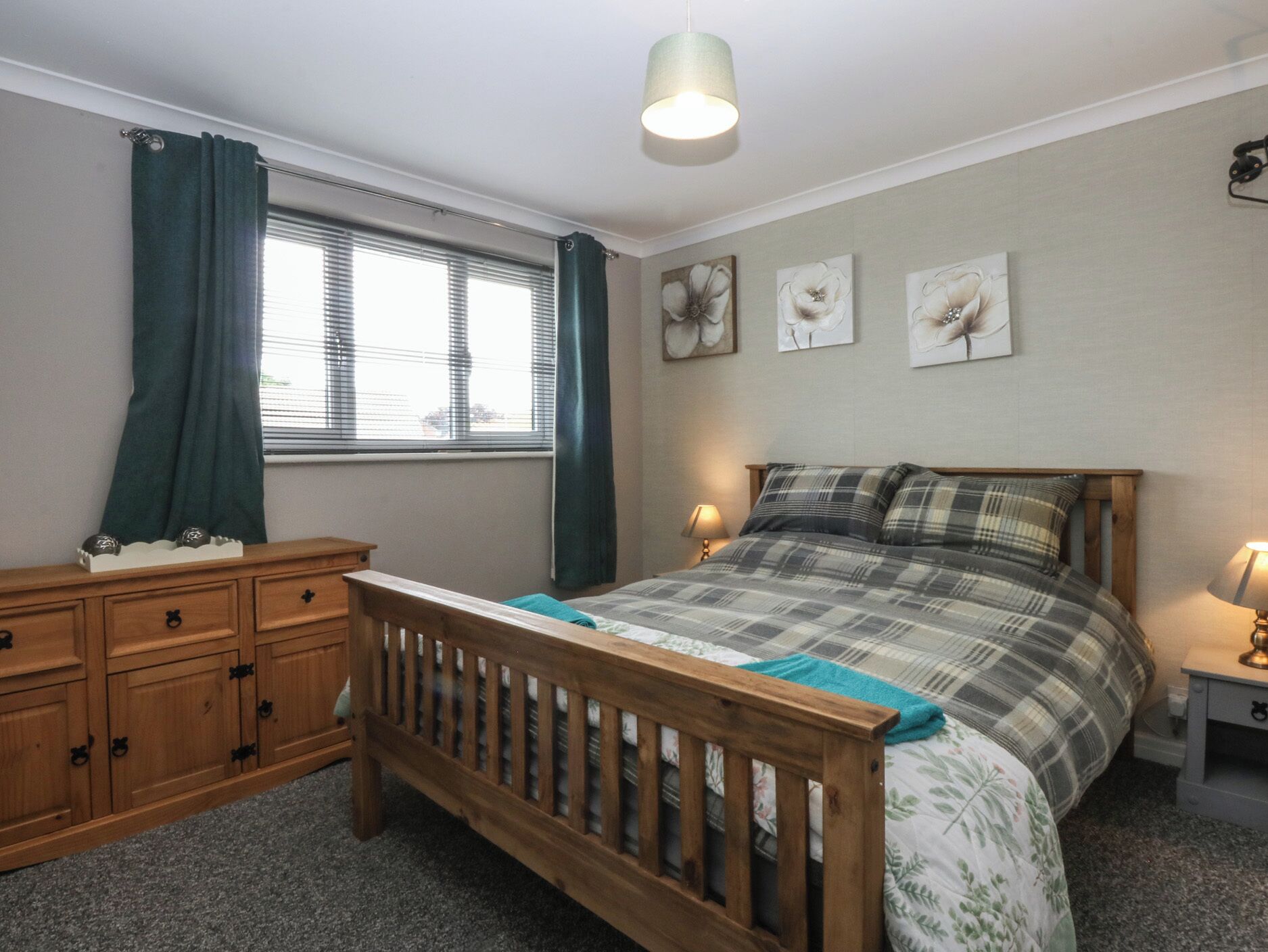Un dormitorio con cama de madera, mesita de noche, cómoda y ventana con cortinas.