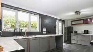 Una cocina moderna con gabinetes grises, un refrigerador negro y un ventanal que proporciona luz natural.