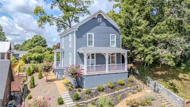 Ein zweistöckiges Haus mit Veranda und Garten.