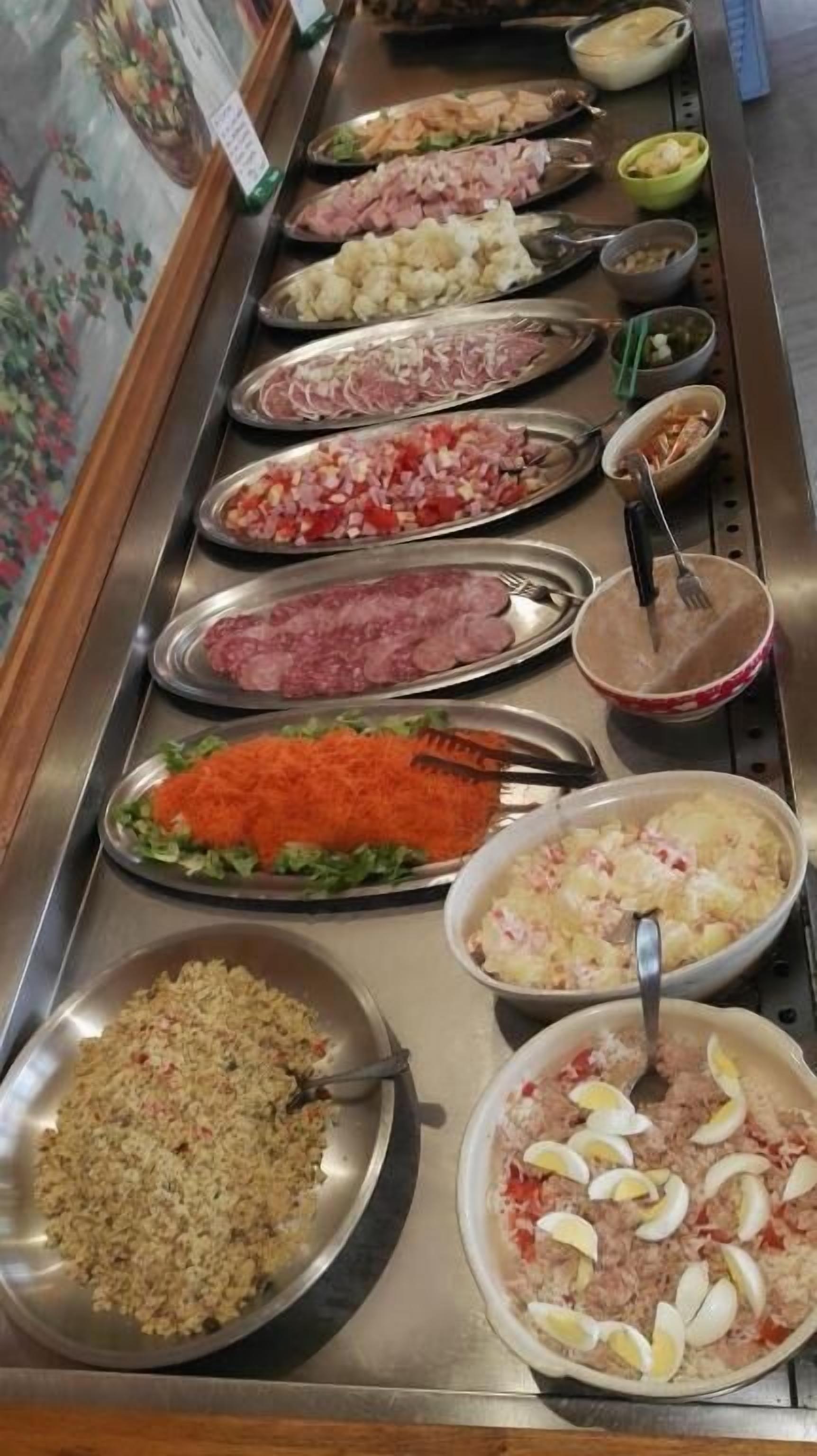 Un bufé con una variedad de platos, incluyendo carnes, ensaladas y arroz.