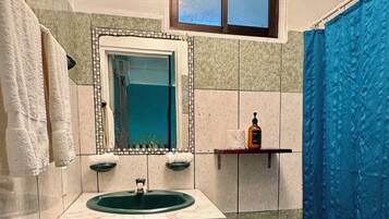 A bathroom with a sink, mirror, toilet, and shower curtain.
