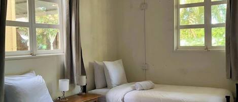 Een kamer met twee bedden, een raam en een airconditioning.